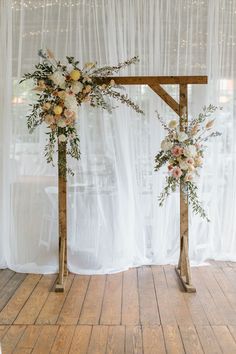 the wedding arch is decorated with flowers and greenery, along with sheer drapes