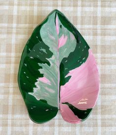 a green and pink leaf shaped dish on a checkered tablecloth