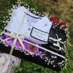 an open gift box filled with clothing and other items on top of a grass covered field