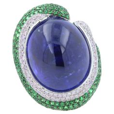 Tanzanite Oval Cabochon 50.00 Carats Dark Sea Blue Color & Hues Tsavorites 1.25 ctw Diamonds 1.25 ctw 18K White Gold 26.80 grams Ring Size 7 31.50 mm length of front ring 24.00 mm width of front ring 7.50 mm back shank width Oval Tanzanite White Gold Jewelry, Fine Jewelry Tanzanite Oval Jewelry, Oval Tanzanite Rings Fine Jewelry, Luxury Oval Tanzanite Jewelry, Oval Tanzanite Gemstones In Silver, Sea Blue Color, Blue Tanzanite, Oval Cabochon, Blue Sea