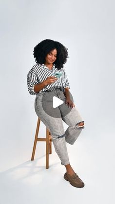 a woman sitting on top of a wooden chair with her arms crossed and looking at the camera