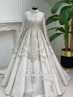 a white wedding dress on display in front of a potted plant