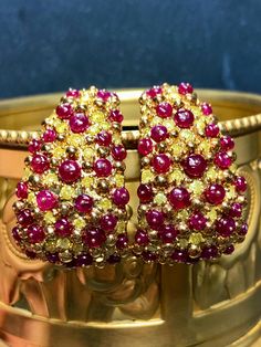 An impressive pair of earrings done in deep 18K yellow gold and set with 3.81cttw in fancy vivid yellow diamonds ranging Si2-I2 clarity as well as 11.12cttw in bright red cabochon rubies (all weights are stamped and exact) . A beautiful pair of earrings that look like no other. They have posts with oversized pushbacks. Dimensions/Weight: Earrings 1.25" by .80" and weigh 27.2g. Condition: All stones are secure and in perfectly wearable condition. E-AHHJ Yellow Diamond Earrings With Gemstone, Gold Multi-stone Diamond Earrings, Gold Diamond Multi-stone Earrings, Exquisite Multi-stone Yellow Gold Earrings, Luxury Gold Clip-on Earrings With Gemstone, Exquisite Yellow Gold Multi-stone Earrings, Gold Diamond Earrings With Multi-stone Detail, Luxury Yellow Gemstone Earrings, Luxury Gold Multi-stone Hoop Earrings