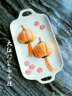 two peeled oranges on a white plate with pink flowers and leaves in the shape of fish