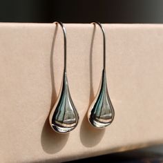 [Details] ✧ Material > sterling silver 92.5% ✧ Color > silver ✧ Size > 8mm(w) x 26mm(h) These beautifully simple Sterling Silver liquid  Drop Earrings have a silver liquid metal effect giving them the fresh flowing appearance of a raindrop. It's contemporary design silver teardrop earrings are simply made to wear with an easy, no fuss fixed hook drop setting. The polished finish and silver liquid metal effect make the earrings appear like recently formed drops of  rain slowly moving over a leaf. Minimalist Silver Long Drop Teardrop Earrings, Artistic Silver Teardrop Jewelry, Minimalist Sterling Silver Water Drop Jewelry, Contemporary Teardrop Silver Jewelry, Modern Sterling Silver Long Drop Teardrop Earrings, Streetwear Jewelry, Water Drop Earrings, Cool Earrings, Liquid Metal