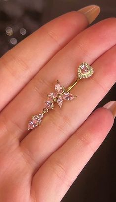 a person's hand holding a gold colored ring with pink stones