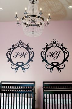 two baby cribs in front of a chandelier