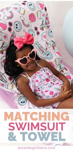 girl laying down on a beach towel that's light pink with blue smiley faces, surfboards, rainbows and hot pink sunglasses on it. She's wearing a matching one piece swimsuit in the same print and has pink heart sunglasses on. Cute Printed Swimwear For Beach Season, Cute Swimwear With Uv Protection For Vacation, Playful Pink Swimwear For Poolside, Playful Swimwear With Adjustable Straps For Summer, Cute Printed Swimwear For Vacation, Cute Printed Swimwear For Poolside, Adjustable Summer Tankini For Swimming, Cute Summer Vacation Swimwear, Cute Summer Swimwear For Vacation