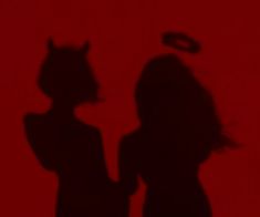 the shadow of two people standing next to each other in front of a red wall