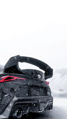 the back end of a black sports car in the snow