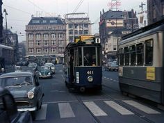 an old trolley car is traveling down the street in front of other cars and buildings