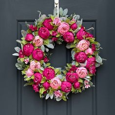 a wreath with pink flowers hanging on a door