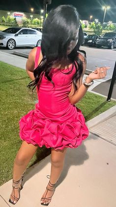 a woman in a pink dress sitting on the sidewalk