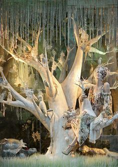 a woman sitting on top of a tree in front of a window with icicles hanging from it