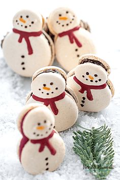 snowmen made out of cookies sitting in the snow next to a pine tree branch