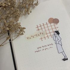 an open notebook with a drawing of a woman talking on a cell phone next to dried flowers