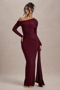 a woman in a long sleeved dress with an off the shoulder drape and side slit