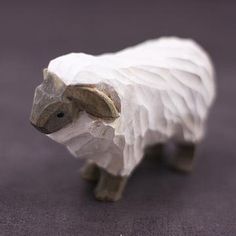 a white sheep figurine sitting on top of a purple tablecloth covered floor