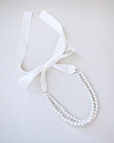 A delicate pearl necklace with a black satin ribbon closure is to add an effortless romantic and classic look to your formal or casual style. Perfect to complete your date night, wedding, bridesmaids, holiday party, and any special occasions. DETAILS:HANDMADEIMPORTED MATERIALS Classic Adjustable Necklaces For Party, Adjustable Pearl Chain Necklace For Formal Occasions, Adjustable Ribbon Wedding Jewelry, Chic Pearl White Necklace For Wedding, Elegant Bridal Accessories With Satin Bow, Adjustable Pearl Charm Necklace For Formal Occasions, Classic Adjustable Pearl Necklace For Party, Adjustable Pearl Bridal Necklace For Party, Chic Pearl Drop Necklace For Wedding