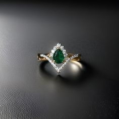 an emerald and diamond ring sitting on top of a black surface with white diamonds around it