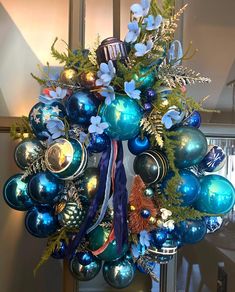 a wreath with blue and green ornaments hanging from it