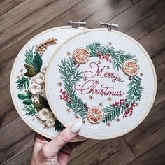 someone is holding up two cross - stitch hoops with the words merry christmas on them