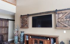 a flat screen tv mounted to the wall in a living room with wooden shutters