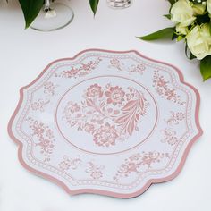 a pink and white plate sitting on top of a table next to vases with flowers