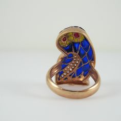 A sterling stunner with plique-a-jour enamel and glittering CZ stones, this size 7 ½ statement ring is certain to get you noticed. Done in a copper overlay that really sets of the cobalt blue body, the Barn Owl also boasts yellow on its face with red in its eyes, while the CZs are perfectly placed to accent its wing. The Bird measures 1 1/8 inches in length and is 5/8 inch wide. It is in excellent, new condition and marked Sezgin, 925 inside the band. Fine Jewelry Enamel Ring Hallmarked, Antique Enamel Ring Collectible, Art Deco Enamel Ring Jewelry, Art Deco Enamel Jewelry Ring, Collectible Hallmarked Enamel Ring In Fine Jewelry Style, Antique Enamel Ring As A Gift, Enamel Multi-stone Rings As A Gift, Fine Jewelry Enamel Ring For Anniversaries, Fine Jewelry Enamel Ring For Anniversary