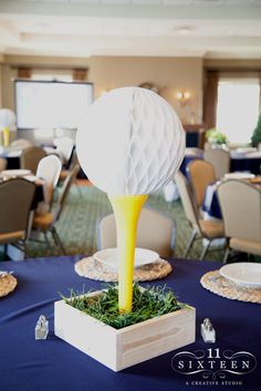 a golf ball on top of a yellow tee in front of a blue table cloth