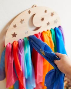 a person is holding scissors in front of a rainbow wall hanging with stars and moon on it