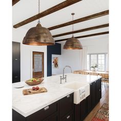 a kitchen with an island, sink and two hanging lights over the stove top area