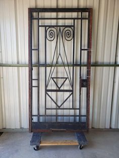 an old wrought iron door sitting on a dolly in front of a metal wall panel