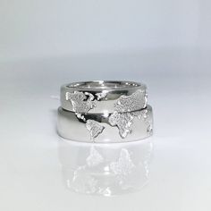 two silver rings with butterflies on them sitting next to each other in front of a white background