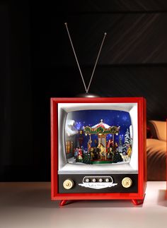 an old fashioned television sitting on top of a table next to a red box with christmas decorations