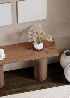 a wooden table with two white vases on it and a plant in the middle