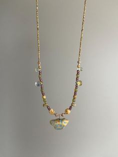 Discover the epitome of bohemian charm with our meticulously handcrafted beaded necklace. Each bead is carefully selected to create a harmonious blend of colors and textures, culminating in an eye-catching ceramic-look glass pendant that boasts an exquisite splash of gold and azure patterns. This one-of-a-kind piece promises to add a touch of artisanal sophistication to any ensemble. Perfect for casual wear or special occasions, this necklace is a testament to timeless style and craftsmanship. T Birthday Cottagecore, Boho Necklace Layering, Layered Necklaces Boho, Cottagecore Jewelry, Diy Jewelry To Sell, Ceramic Color, Tourmaline Beads, Funky Jewelry, Jewelry Studio