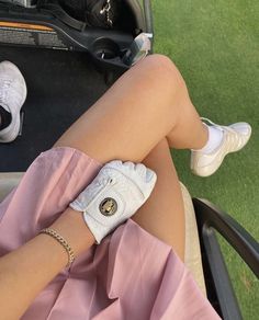 a woman sitting on top of a chair next to a golf bag and holding onto her arm