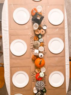 an overhead view of a table with plates, cups and pumpkins on the top