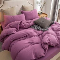 a bed with purple comforter and pillows on it