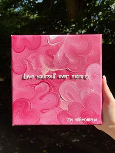 someone holding up a pink box with the words love yourself ever more