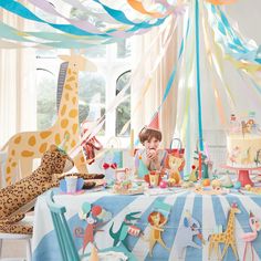 children at a birthday party with colorful streamers and giraffes on the table