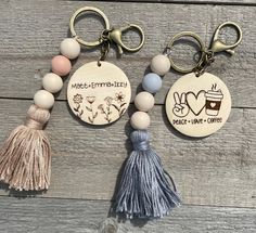 two wooden key chains with tassels attached to each other on top of a wooden surface