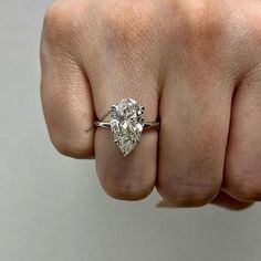 a woman's hand with a diamond ring on her finger, showing the center stone