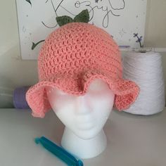 a white mannequin head wearing a pink crocheted hat