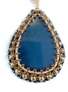 a blue tear shaped pendant with gold beads