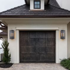 a large garage door with two lights on the side of it and a brick walkway in front of it