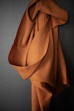 an orange cloth hanging on the wall next to a gray wall with a black background