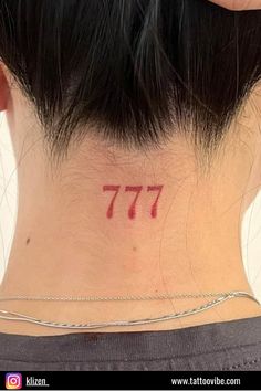 the back of a woman's neck has a small red number tattoo on it