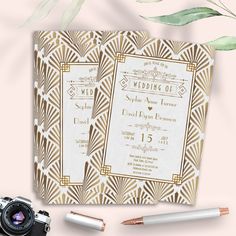 the wedding stationery is laid out next to a camera, pen and pencils